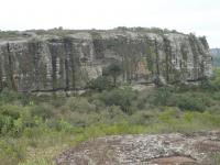 Paredões verticais de rocha conglomerática com estratos sedimentares com formato tabular são coberto por vegetação rupestre. Fotografia: Carlos Peixoto, 2014.