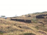 ruinas de antigas casas coloniais construídas com canga ferruginosa, na área da mineração, onde também estão os poços (buracos de sarilhos, galerias, mundeus, canais, pilhas de rejeito, etc.